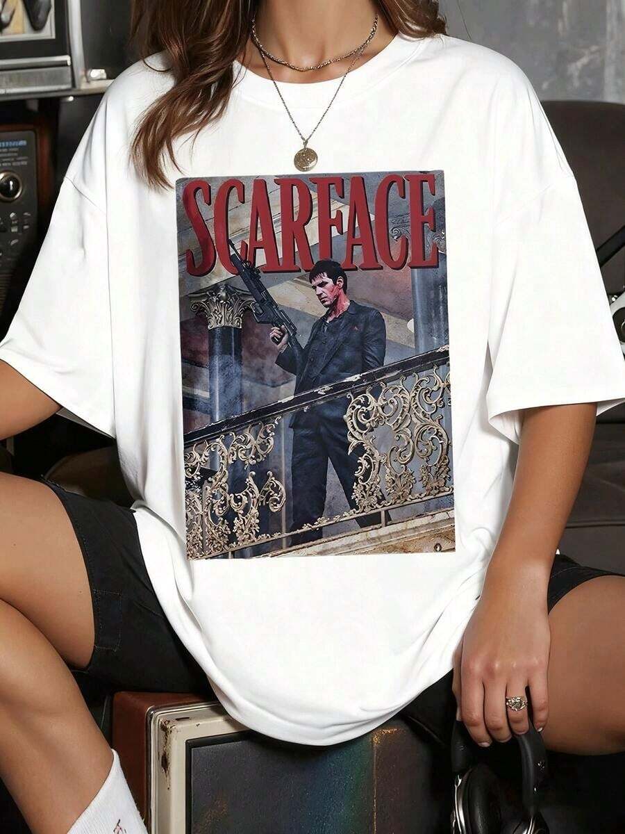 SimpieAndVersatileDesignLa imagen del icónico Tony Montana de representa la ambición inquebrantable y el poder su figura desafiante con un arma en un balcón ornamentado evoca un legado cinematográfico inolvidable Camiseta de mujerCottonT-Shirt - Blanco - Ver 1