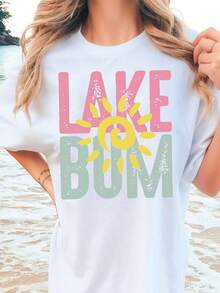 Camiseta blanca, con las palabras "LAKE" escritas en letras rosas y "BUM" en letras verdes, con un sol amarillo en el medio.   Camiseta de manga corta de gran tamaño con estampado de letras, cuello redondo estándar, tejido de algodón puro, cómodo y transpirable. - Blanco - Ver 1