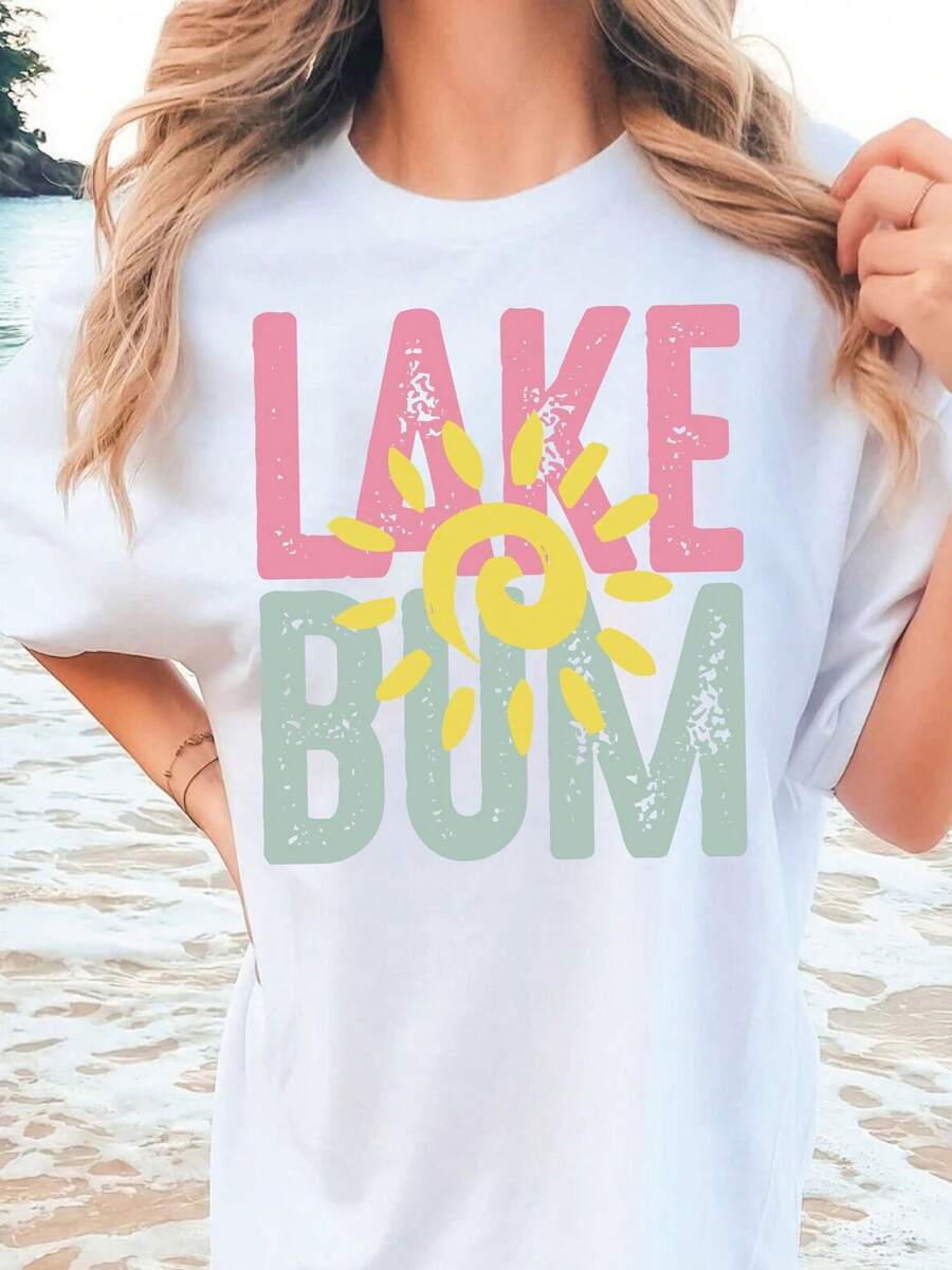 Camiseta blanca, con las palabras "LAKE" escritas en letras rosas y "BUM" en letras verdes, con un sol amarillo en el medio. Camiseta de manga corta de gran tamaño con estampado de letras, cuello redondo estándar, tejido de algodón puro, cómodo y transpirable. - Blanco - Ver 1