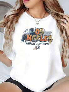Ciudad moderna con siluetas urbanas y letras vibrantes que celebran la energía del fútbol y la emoción del torneo mundial 2026 en Los Ángeles inspirando pasión deportiva camiseta de mujer casual cómoda para fanáticas del deporte - Negro - Ver 1