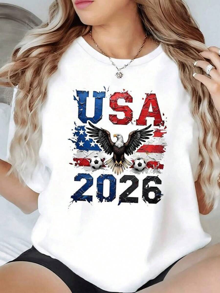 Águila majestuosa extendiendo sus alas frente a la bandera de Estados Unidos junto a balones de fútbol simbolizando fuerza y orgullo nacional rumbo al torneo 2026 camiseta de mujer casual moderna cómoda para fanáticas del deporte patriótico - Negro - Ver 1