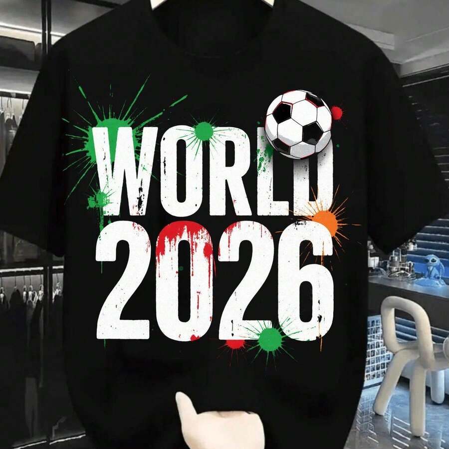 2026 World Cup Football Shirt, Bold White Text With Red Paint - 2026 Splatters And Green Splatters Around The World, Black And White Football Near The 'O', Brown Wristwatch In Hand Holding The Shirt, Casual Crew Neck T-Shirt For Football Fans, Sh Indoor Shop - 黑 - 查看 1