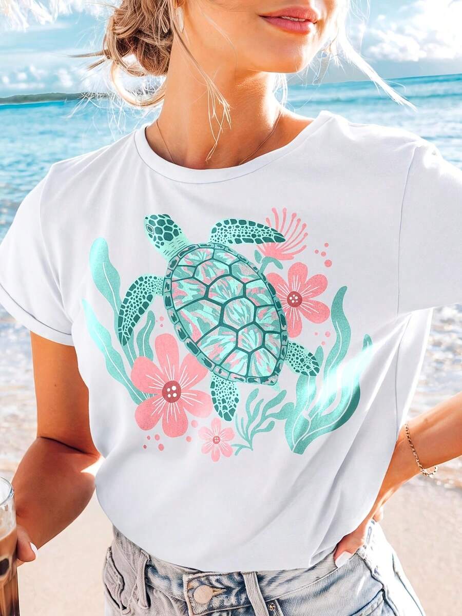 Camiseta blanca con estampado de tortuga. La tortuga es de color turquesa y azul, rodeada de flores rosas y hojas turquesas. Esta camiseta es corta y tiene cuello redondo, lo que la hace perfecta para días de playa, fiestas de adultos y celebraciones de temporada. - Blanco - Ver 1