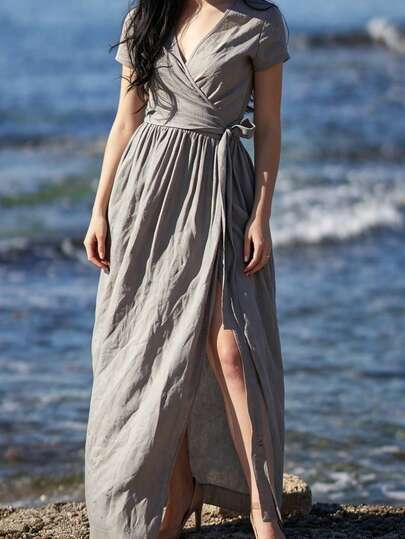 Plus Size Women's Solid Color Linen Maxi Dress, V-Neck Criss-Cross Design Elegant & Slimming, Loose Fit Accommodates Various Figures. The Flowing Hem Of The Dress Blowing In The Wind On The Rocky Beach Showcases The Beauty Of Natural Movement. Lightweight Breathable Fabric Suitable For Summer Vacation Wear
