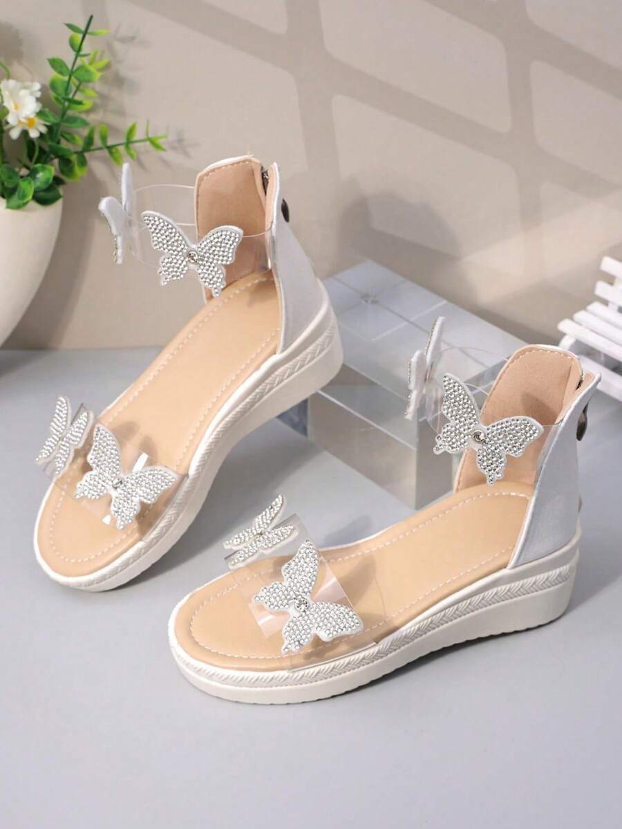 Nuevas sandalias con cuña para niños, decoradas con mariposa y perla, sandalias romanas de verano para niñas con lazo, suela gruesa, estilo de campus de playa con puntera abierta, cremallera trasera antideslizante - Beis - Ver 1