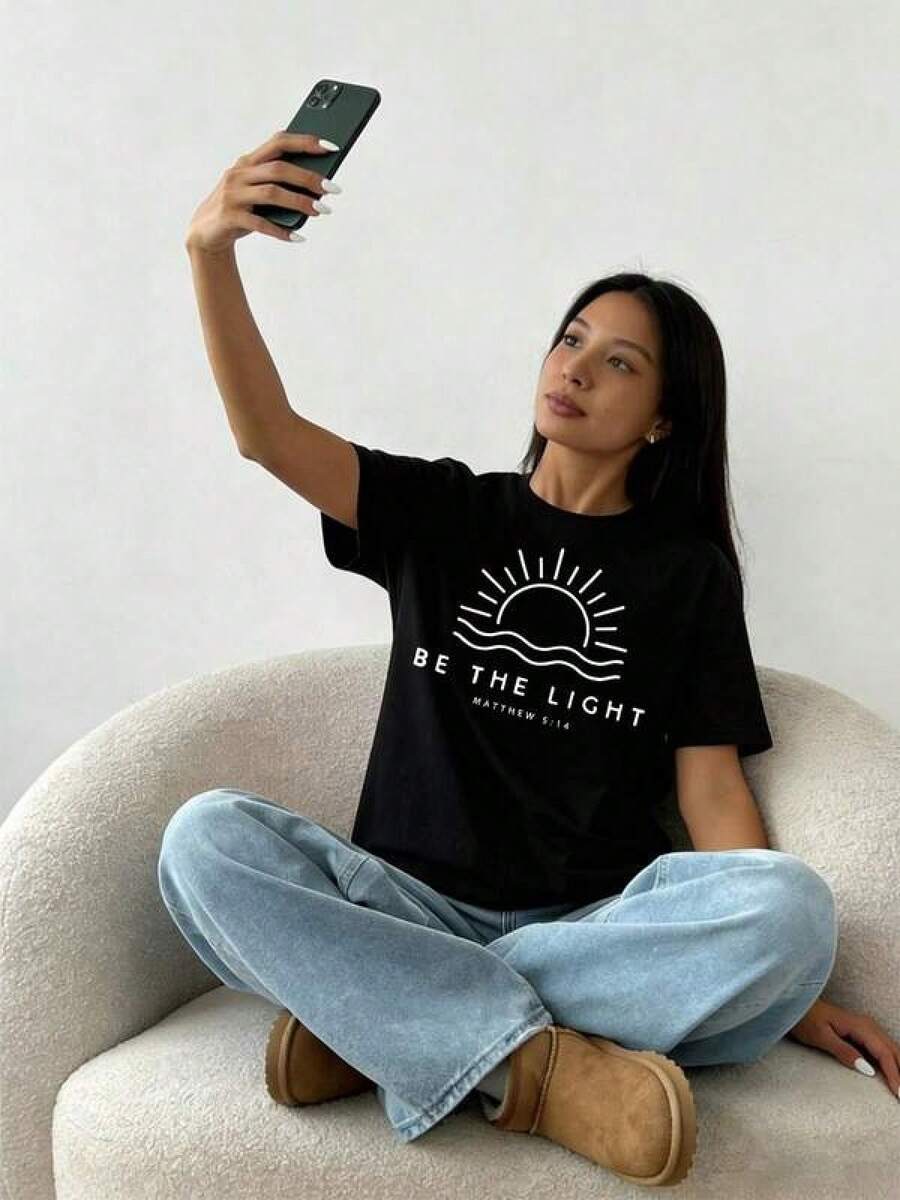 Camiseta única Be The Light diseño y2k con estampado de sol inspirador, perfecta para transmitir positividad y estilo, ideal para cualquier ocasión y  de moda en México, destaca tu personalidad y sé un faro de luz en tu vestuario. Cómoda y versátil para escuela, trabajo, salidas y eventos casuales - Negro - Ver 1
