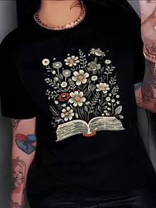 Libro abierto del que brotan flores silvestres simbolizando conocimiento que florece y conexión entre la naturaleza y la imaginación camiseta de mujer casual moderna cómoda - Negro - Ver 8