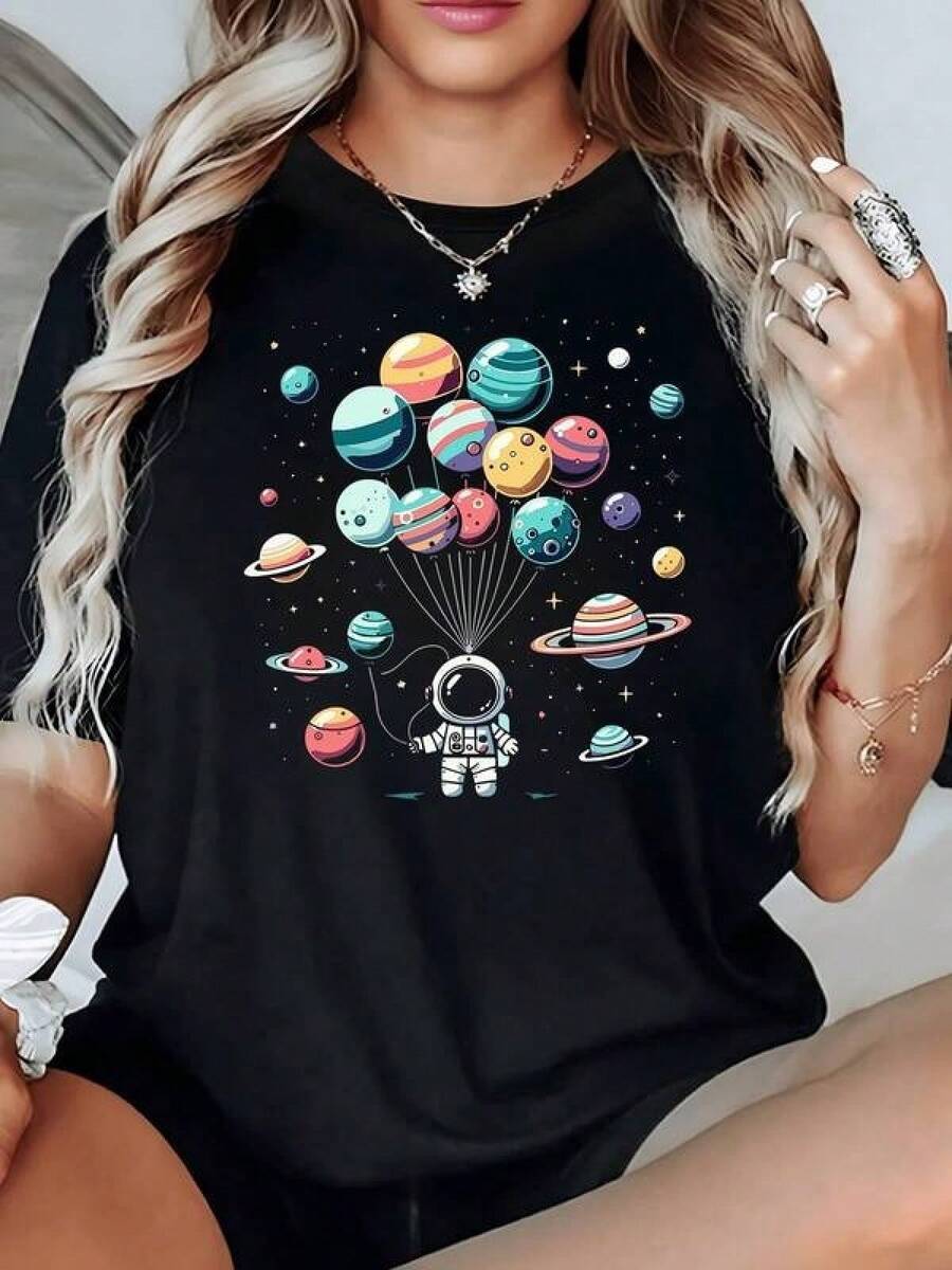 Astronauta sosteniendo globos que parecen planetas simboliza la curiosidad humana y el deseo de explorar universos infinitos en armonía camiseta de mujer 100% algodón - Negro - Ver 1