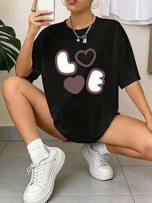 Primavera/Verano 2026, nueva camiseta de mujer para el Día de San Valentín, de corte holgado, con hombros descubiertos, mangas cortas y estampado de "combinación de corazones en colores contrastantes". Diseño sencillo y lindo, cómoda y agradable al tacto. Ideal para quienes prefieren un estilo suave y lindo en situaciones casuales del día a día. Camiseta de manga corta. - Negro - Ver 6