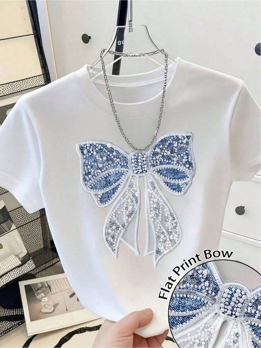 Estilo Holgado de Talla Grande con Apliques Bordados - Nueva Colección de Moda Femenina Primavera/Verano 2026, con un Diseño Único, Dulce y Juvenil, con un Aplique de Lazo de Perlas y Lentejuelas en una Camiseta de Manga Corta con Cuello Redondo, Camiseta Básica Holgada e Informal, Adecuada para el Traslado Diario y las Citas, Camiseta Versátil, Ropa Urbana para Salidas Cotidianas, Lavable a Máquina. - Blanco - Ver 1