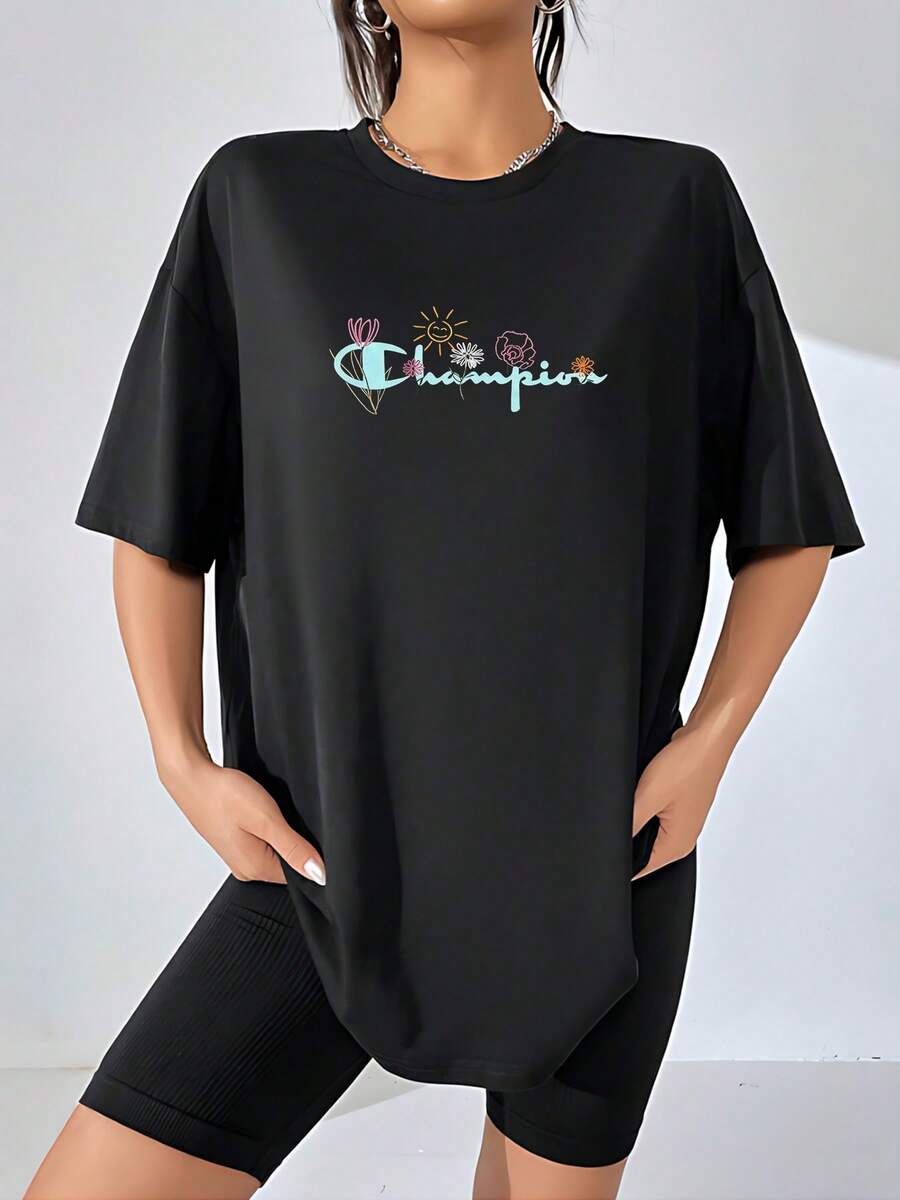 El divertido y alegre logo de Champion cobra vida con un toque de naturaleza y optimismo, luciendo flores delicadas y un sol sonriente que irradia felicidad. Esta camiseta de mujer, confeccionada en, celebra la alegría de vivir y la belleza efímera. Perfecta para un look casual y vibrante, esta camiseta combina comodidad y un mensaje positivo para alegrar tu día a día. camiseta de mujer - Negro - Ver 1
