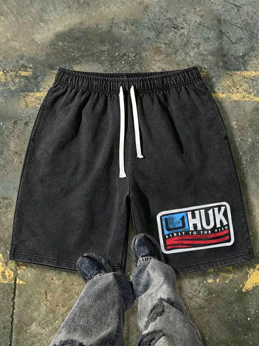 230g Washed Denim Shorts Featuring The Classic HUK Brand Emblem In A Red And Blue Flag-Inspired Color Scheme, With The Brand Slogan "FIRST TO THE FISH" Printed Below. These Men's Retro Washed Denim Shorts Are A Casual, Street-Style Piece Inspired By American Fishing Culture. Comfortable And Breathable, Suitable For Everyday Wear, They Include An Adjustable Drawstring Waist, Elastic Waistband, And Pockets. - Black - View 1