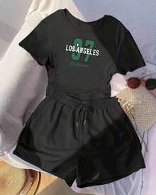 Una camiseta de manga corta para mujer con estilo retro americano, de corte holgado y con diseño estampado (los pantalones son solo para sugerencias de estilo). Esta pieza sencilla y elegante presenta un patrón de letras impresas con temática tropical, lo que la convierte en un elemento imprescindible para crear un look relajado de vacaciones, perfecto para ocasiones como el Día del Trabajo y el Día de la Independencia de México. - Negro - Ver 1