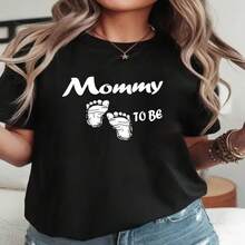 Camiseta de maternidad de talla grande para mujer, adecuada para anuncio de embarazo y baby showers - Top elástico de manga corta y cuello redondo con estampado de "Futura Mamá" y huellas de pies, blusa casual de primavera verano para futuras mamás S-XXXL - Negro - Ver 1
