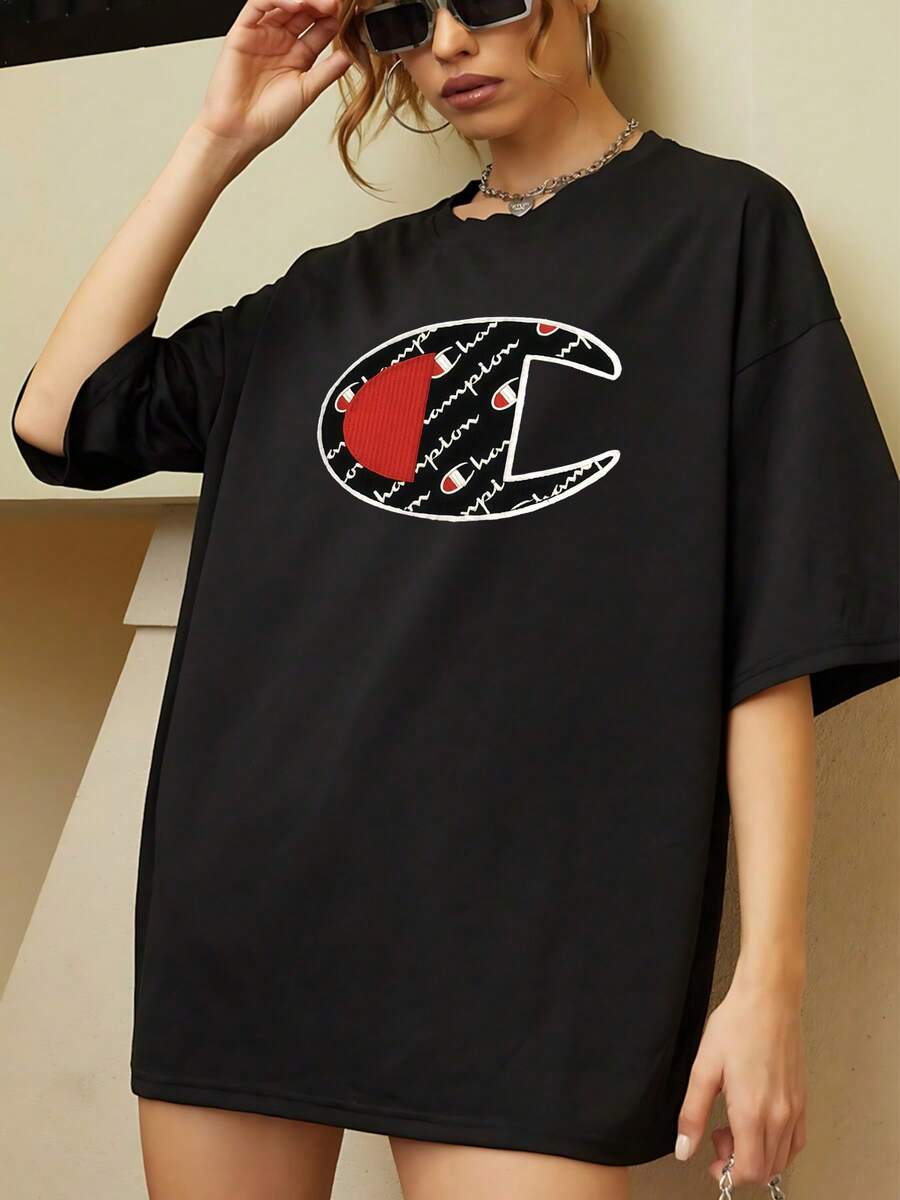 El llamativo logo en forma de C, superpuesto con el nombre Champion repetido en escritura cursiva sobre un fondo negro y detalles en rojo vibrante, representa la culminación de la excelencia deportiva y el espíritu de superación. Esta camiseta, confeccionada con, celebra la victoria y la dedicación, vistiendo al usuario con la esencia de un verdadero campeón. Es perfecta para lucir un look casual con un toque audaz y lleno de significado, camiseta de mujer, moda urbana, prendas deportivas, comodidad garantizada. - Negro - Ver 1