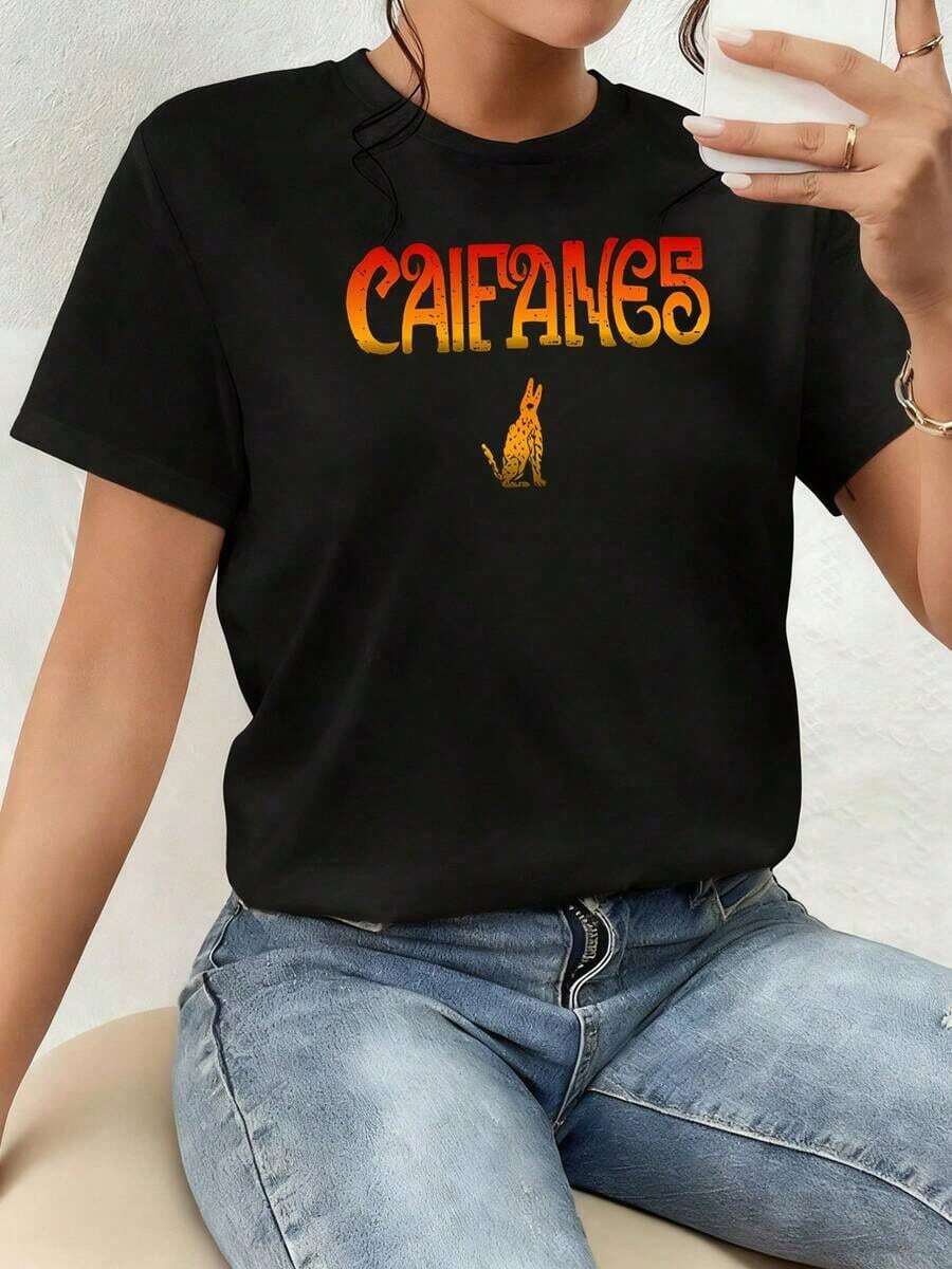 Art T-Shirt. The Pattern Displays The Word Caifanes In Warm Tones That Evoke Energy And Passion, Alongside The Silhouette Of A Golden , A Symbol Of Strength And Mysticism. Women's 100% Cotton T-Shirt, Comfortable And Modern For Everyday Wear. - 黑色 - 查看 1