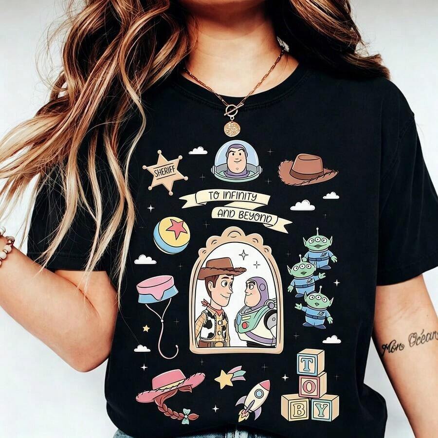 (Authorized By Disney. Mickey Mouse) The Front Features The Famous Retro-Style Scene Of Woody And Buzz Lightyear Looking At Each Other, Complete With Cowboy Hat, Space Helmet, Alien, Spring-Loaded Dog Collar, Jessie's Hat, The Pisa Planet Logo, The Letter "TOY" Made Of Building Blocks, And Other Iconic Elements. The Classic Phrase "TO INFINITY AND BEYOND" Is Prominently Displayed In The Center. There's Also A Selection Of Stylish Women's T-Shirts Made From Pure Cotton. The Fabric Is Soft, Comfortable, And Breathable, Making It Perfect For Everyday Wear, Shopping, Travel, Parties, And Lounging At Home. Suitable For Both Women And Men, These Garments Also Make Excellent Gifts. Every Woman Should Own One. - màu đen - Xem 1