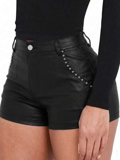 Quần short nữ màu đen phủ lớp vải bóng, điểm nhấn là các chi tiết đinh tán và khóa kéo, kiểu dáng ống đứng, độ co giãn vừa phải tạo cảm giác thoải mái khi mặc.