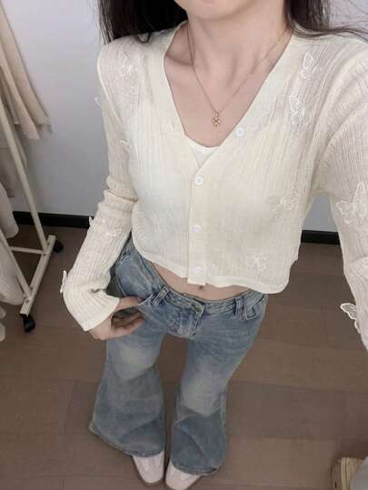 Áo khoác cardigan nữ màu trắng dáng ngắn, cổ chữ V, tay dài, điểm xuyết họa tiết bướm tinh tế.