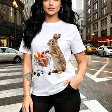 Camiseta de mujer con estampado whimsical de conejo marrón junto a carrito de compras lleno de zanahorias naranjas - camiseta casual de manga corta y cuello redondo, ajuste cómodo y moderno para el estilo urbano - ideal para paseos por la ciudad, sal - Blanco - Ver 10