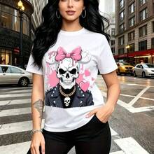 Camiseta de mujer con estampado de calavera rosa con lazo y cadenas doradas sobre fondo urbano - camiseta casual de manga corta, ajuste cómodo y moderno, estilo alternativo y urbano ideal para paseos por la ciudad, salidas con amigas o días lluviosos - Blanco - Ver 1