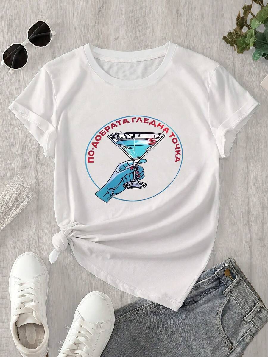Una mujer con una blusa de manga corta y cuello redondo sostiene una copa de martini en la mano. El estampado de la copa de martini es adecuado para todas las estaciones. - Blanco - Ver 1