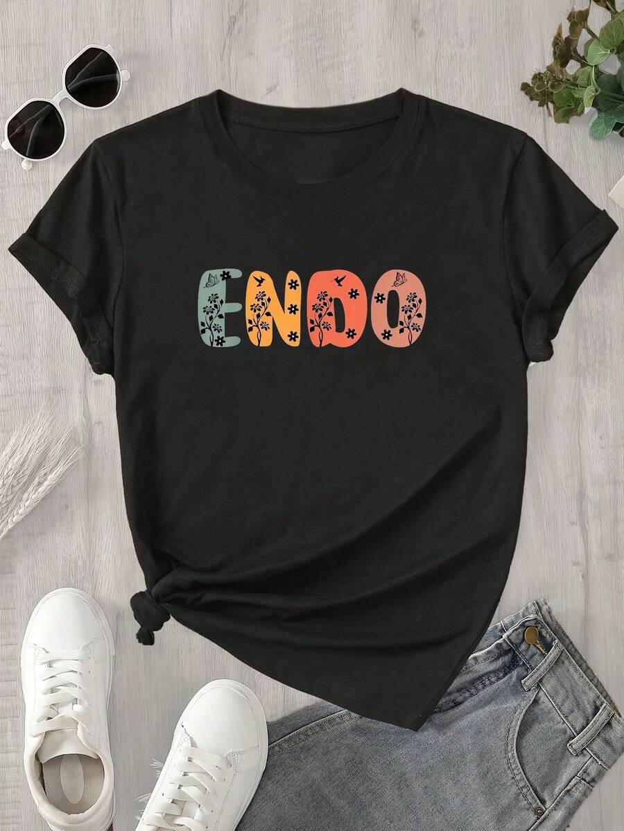 Top de mujer de manga corta y cuello redondo con estampado floral y de hojas sobre fondo naranja, apto para todas las estaciones. - Negro - Ver 1