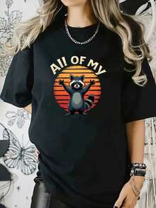 Esta camiseta presenta un divertido mapache con las patas levantadas sobre un atardecer retro, combinado con - Negro - Ver 1