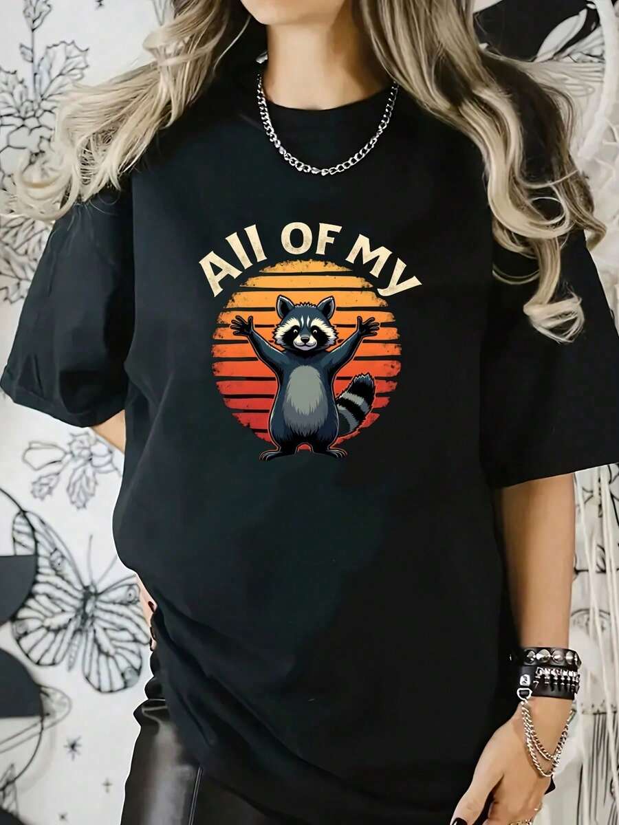 Esta camiseta presenta un divertido mapache con las patas levantadas sobre un atardecer retro, combinado con - Negro - Ver 1