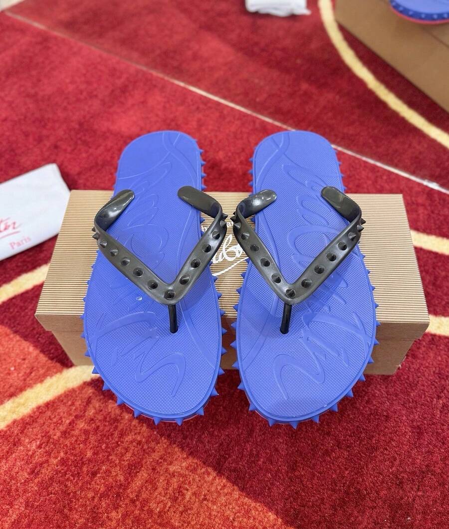 Chanclas CL negras con tachuelas y la icónica suela roja, un calzado de playa veraniego de lujo.