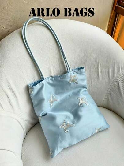 淺藍色緞面飛鳥刺繡托特包，滿幅白色飛鳥刺繡，優雅靈動，鬆軟包身可收納書籍、陽傘、個人物品，淺藍色清爽溫柔，百搭棉麻裙、針織毛衣，營造清涼愜意的中式風情，適合溫婉中式風女孩、學生、上班族，適用校園課堂、日常通勤、春夏短途旅行