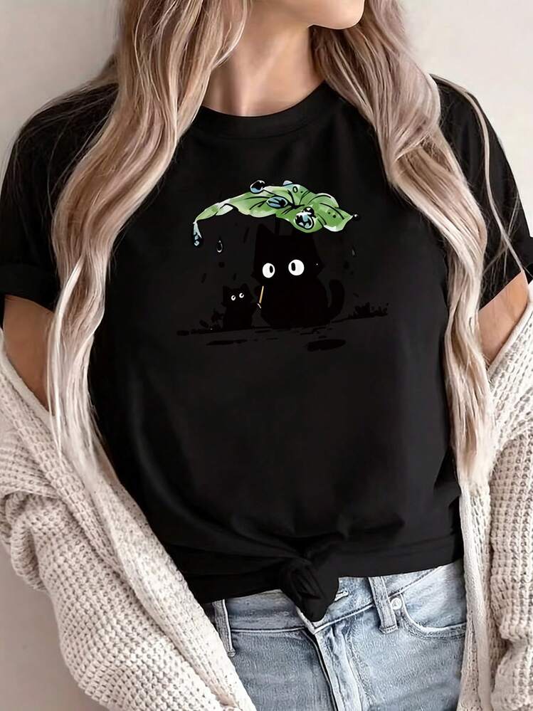 Camiseta de manga corta con cuello redondo que presenta un estampado de dibujos animados de dos gatos negros bajo la lluvia, con el gato más grande usando una hoja de loto para proteger al m - Negro - Añade 1