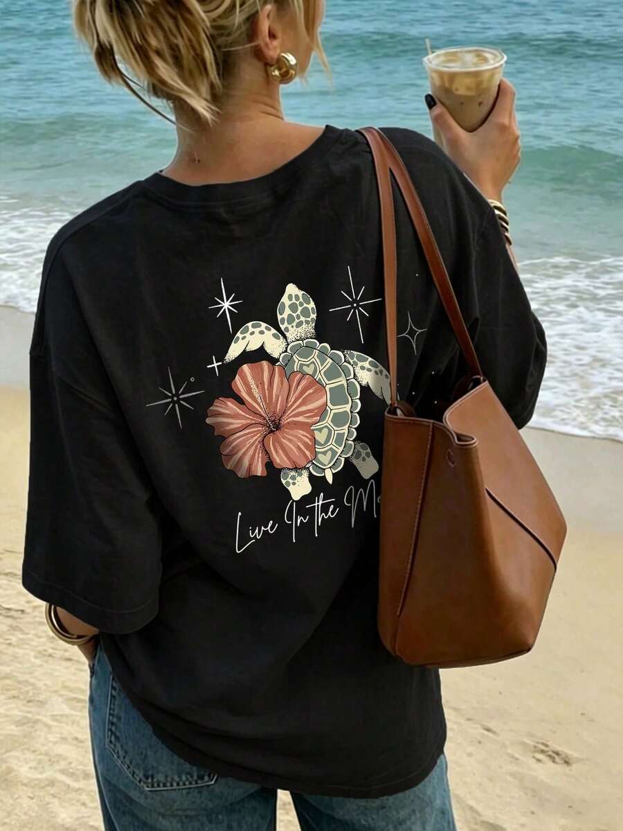 Camiseta casual holgada de cuello redondo con estampado de tortugas, flores y letras para vacaciones en la playa, top femenino elegante de verano, ropa casual deportiva, atuendo para citas y - Negro - Ver 1