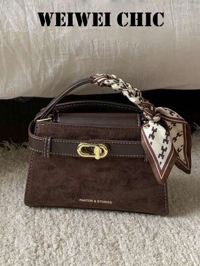 Tas Mini Suede Cokelat Tua dengan Trim Halus Kontras, Dekorasi Kunci Putar Emas, Syal Sutra Bermotif Kepang, dan Tali Selempang yang Dapat Dilepas.