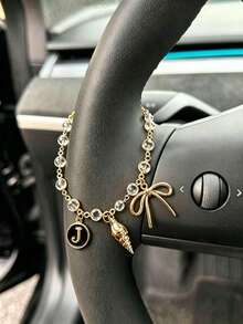 1 pieza Cadena de volante de coche con dije de letra inicial de concha y lazo de strass en tono dorado, estilo bohemio, cadena de metal para decoración interior de automóvil, accesorio ornamental personalizado para vehículo - A - Ver 9