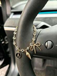 1 pieza Cadena de volante de coche con dije de letra inicial de concha y lazo de strass en tono dorado, estilo bohemio, cadena de metal para decoración interior de automóvil, accesorio ornamental personalizado para vehículo - A - Ver 6