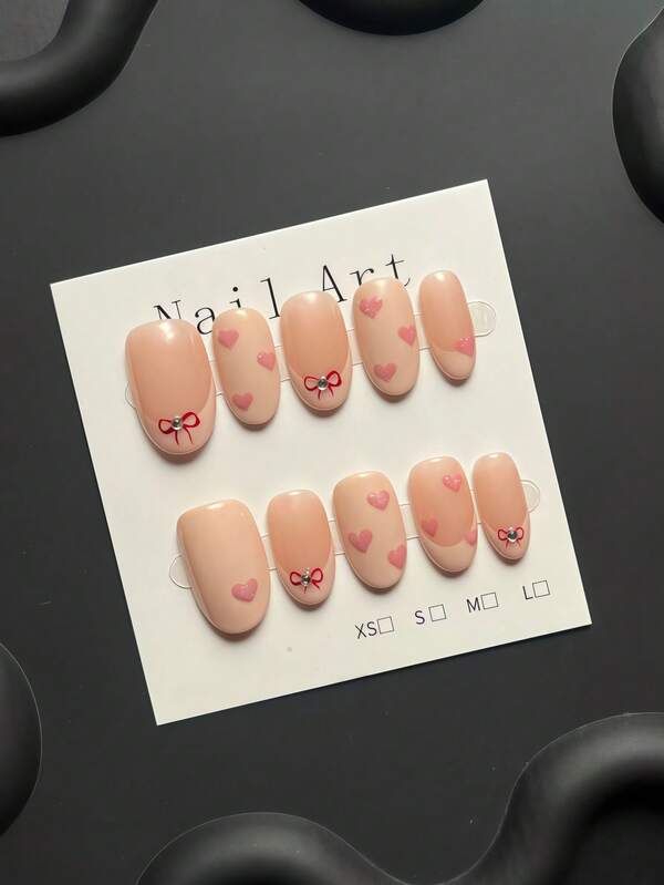 10-Piece Handmade Press-On Nail Kit, Short Oval Shape | Nude Base, Sweet And Innocent Style, Hand-Painted Mini Red Bow And Glittery Heart Embellishments. Perfect For Everyday Commuting And Dates. The Best Gift For Ladies And Girls.