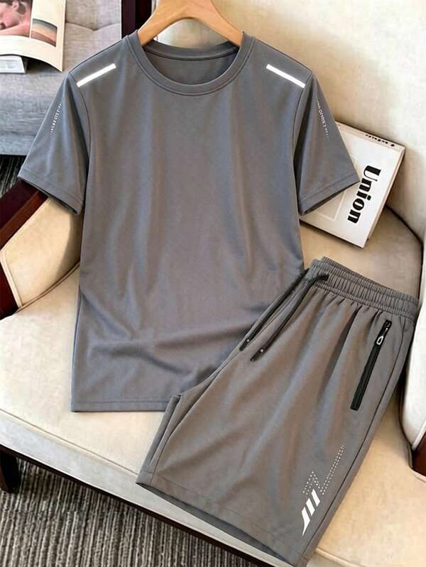 Conjunto de 2 piezas de verano para hombre, gris oscuro delgado, camiseta de cuello redondo de manga corta, pantalones cortos deportivos casuales, franja reflectante en la manga y la pierna del pantalón, decoración reflectante de rayo, bolsillo con cremallera anti-caída, cintura ajustable con cordón