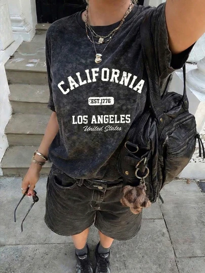 Áo thun dáng rộng, kiểu vintage 1776 Los Angeles, California - Áo phông in hình phong cách retro sinh viên | Giặt tẩy nhẹ, phù hợp với phong cách đường phố bờ Tây | Thiết kế chữ mài mòn, hoàn hảo cho phong cách cô gái California phóng khoáng, phong cách LA, mùa hè đi biển và mặc thường ngày. Màu đen.