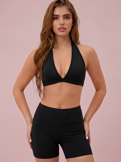 Bộ đồ thể thao Xuân/Hè 2026 màu đen: Áo crop top hở lưng cổ yếm cổ chữ V sâu và quần short ôm sát cạp cao.