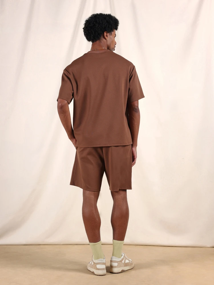 Brązowy T-shirt z krótkim rękawem i pasujące do niego spodenki. Dwuczęściowy, swobodny komplet z okrągłym dekoltem i luźnym krojem zapewniającym codzienny komfort.