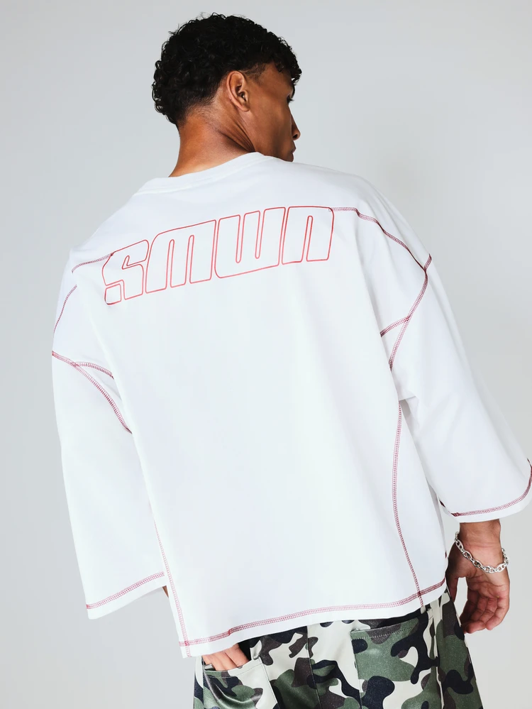 Camiseta corta y ancha con detalles de pespunte rojo en contraste y estampado de logo en la espalda