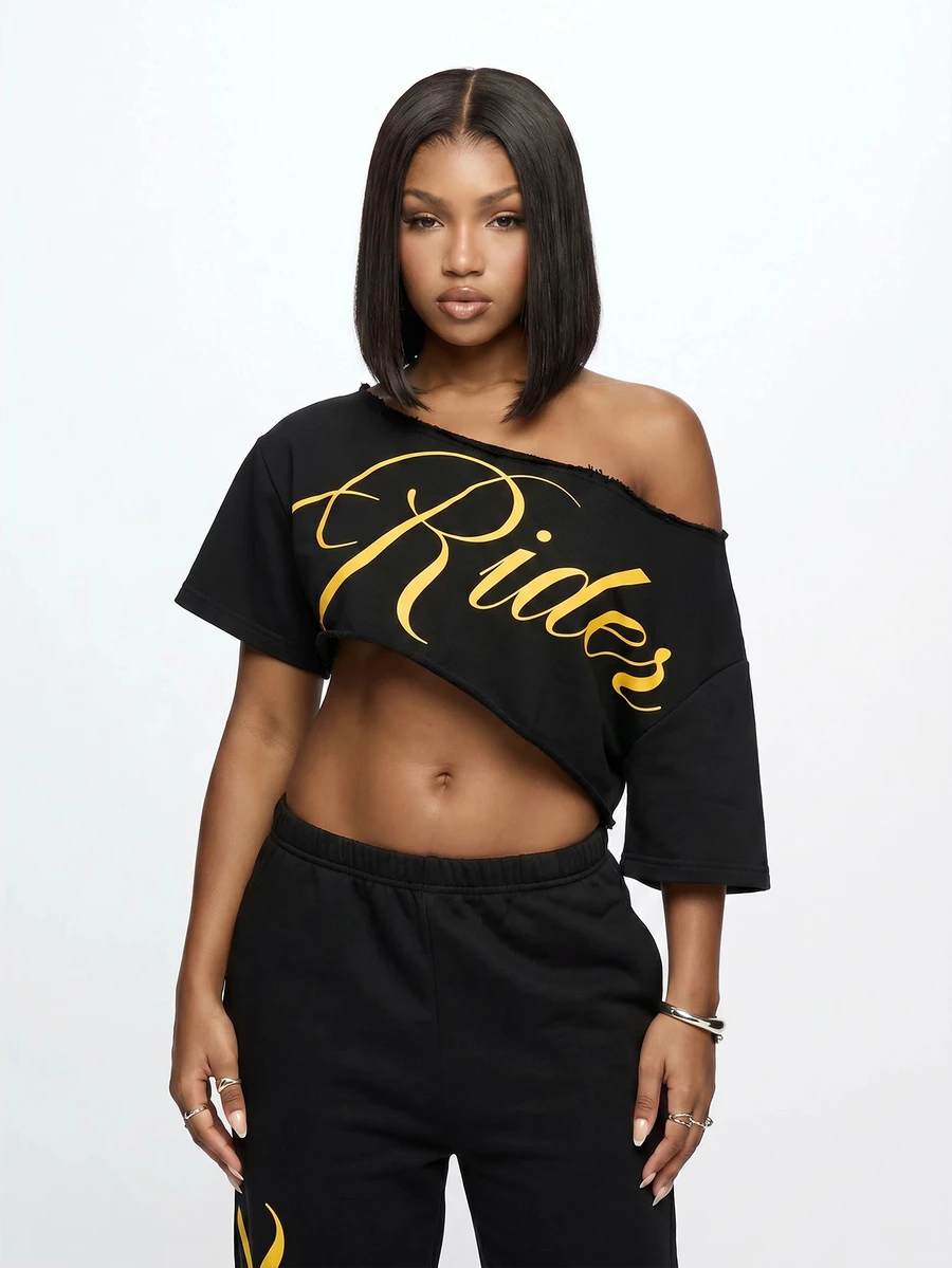SUMWON WOMEN Off-Shoulder Crop Tee With Diagonal Raw Hem Cut And Gold Script Graphic Print - Black - View 1