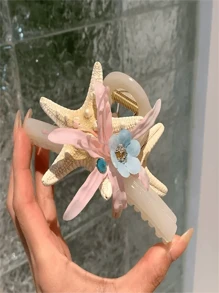 Um novo tipo de presilha de cabelo com flor de concha marinha, adequado para penteados durante férias na praia. Possui um formato de coque que fica na parte de trás da cabeça e vem com uma presilha de cabelo. O adereço de cabeça apresenta um design em forma de tubarão com um lado rosa e um lado azul. É um presente para as senhoras e adequado tanto para uso diário quanto para styling de moda.