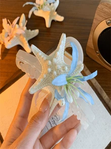 Um novo tipo de presilha de cabelo com flor de concha marinha, adequado para penteados durante férias na praia. Possui um formato de coque que fica na parte de trás da cabeça e vem com uma presilha de cabelo. O adereço de cabeça apresenta um design em forma de tubarão com um lado rosa e um lado azul. É um presente para as senhoras e adequado tanto para uso diário quanto para styling de moda.