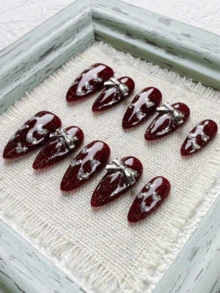 圣诞新年节日氛围，10片红色长杏仁形美甲贴片，饰以优雅的心形闪粉和金属蝴蝶结，尽显高端质感。纯手工制作，可佩戴，全粘可卸，适合上班族、学生、派对女孩以及各种场合的美甲爱好者。套装包含1支果冻胶和1把指甲锉。手工美甲贴片 - 紅色 - 查看 2