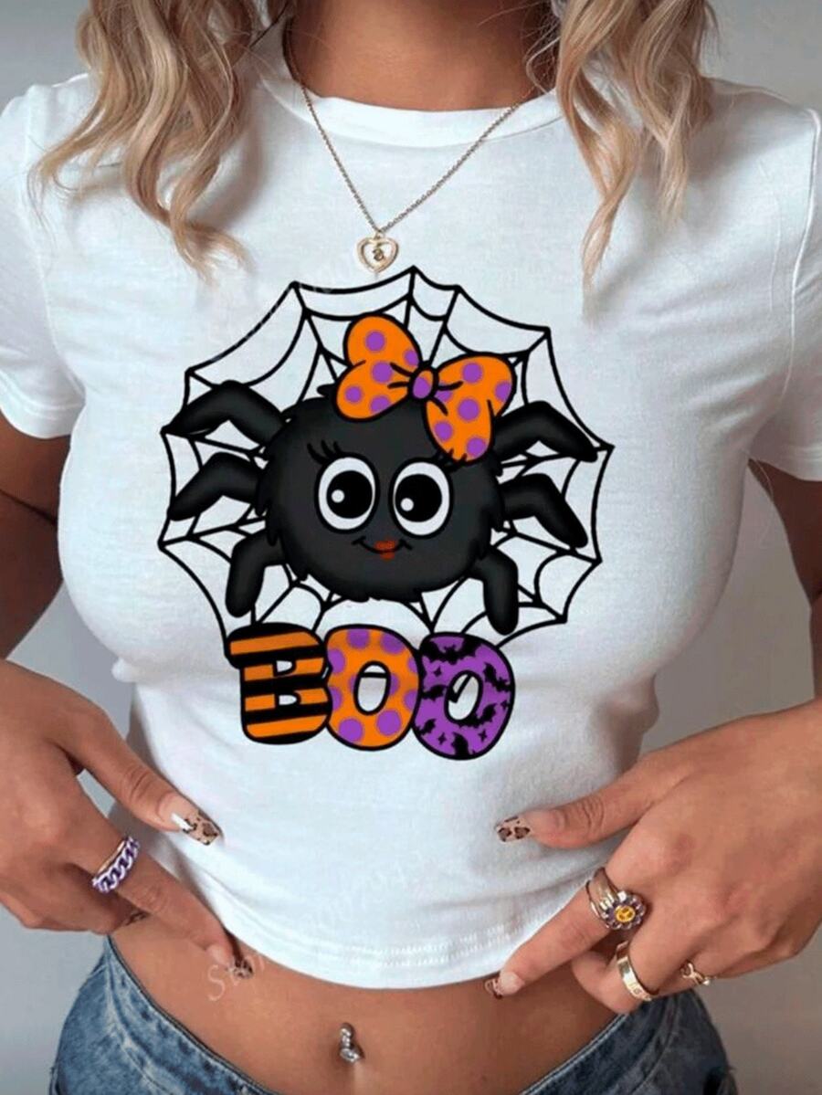Playera estampada color blanca para mujer con diseño divertido y festivo de araña negra con moño naranja con lunares morados sobre telaraña acompañada de la palabra "BOO" en letras grandes y coloridas con estampados de rayas, murciélagos y puntos, ideal para un look juvenil, moderno y alegre en la temporada de Halloween y otoño - Blanco - Ver 1