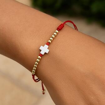 1条极简风格红色绳编十字手链，饰以金属珠，寓意吉祥护身符