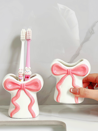 这款设计精美、造型可爱的树脂牙刷架，饰有丝带蝴蝶结，可收纳牙刷、牙膏和化妆刷。它是一款非常实用的家居和浴室用品，也是节日礼物的绝佳选择。