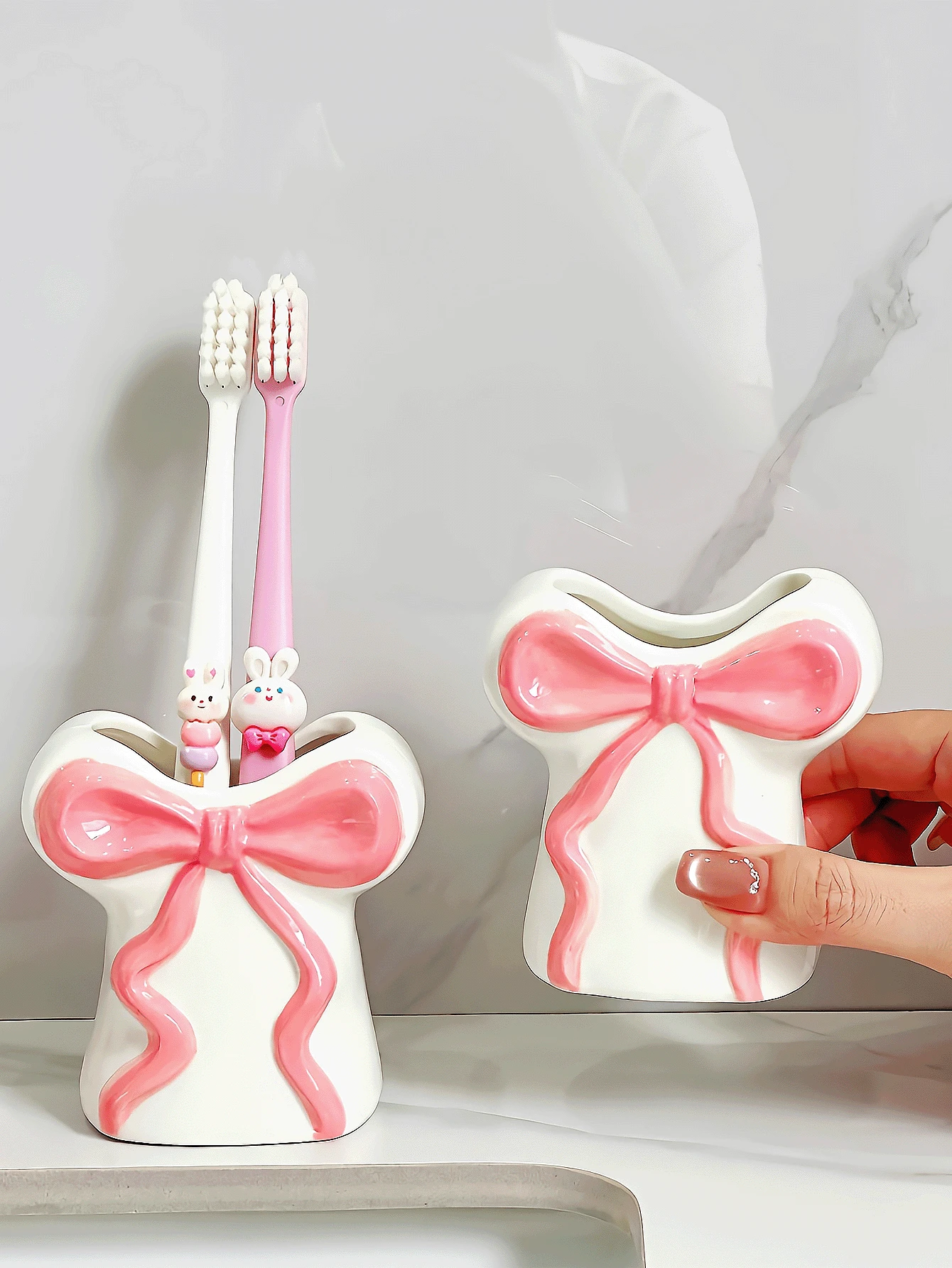 Hộp đựng bàn chải đánh răng bằng nhựa resin đáng yêu và được thiết kế sáng tạo này, với điểm nhấn là chiếc nơ ruy băng, có thể dùng để đựng bàn chải đánh răng, kem đánh răng và cọ trang điểm. Đây là một phụ kiện gia đình và phòng tắm vô cùng thiết thực, đồng thời cũng là một lựa chọn tuyệt vời cho quà tặng dịp lễ.